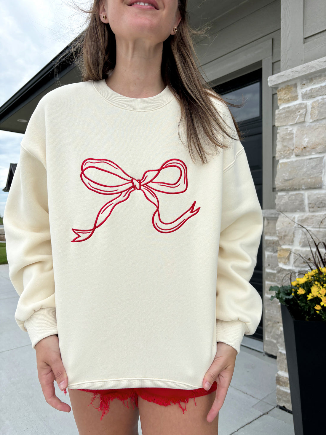 graphic detail of Carlton cream and crimson bow sweater, 100% polyester, shown in size medium